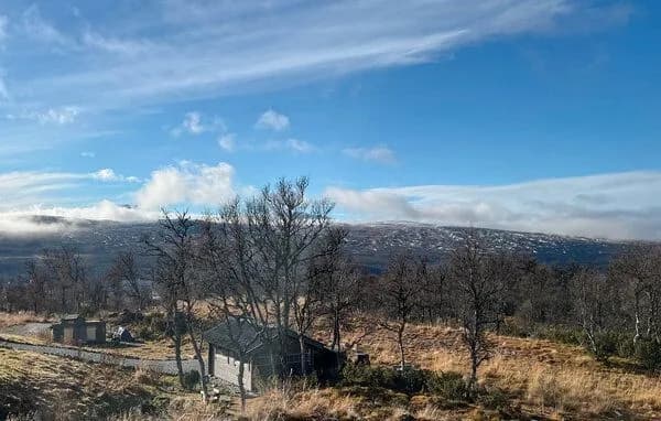 Utsikt over fjellterrenget med skyer som driver over toppene en klar dag.